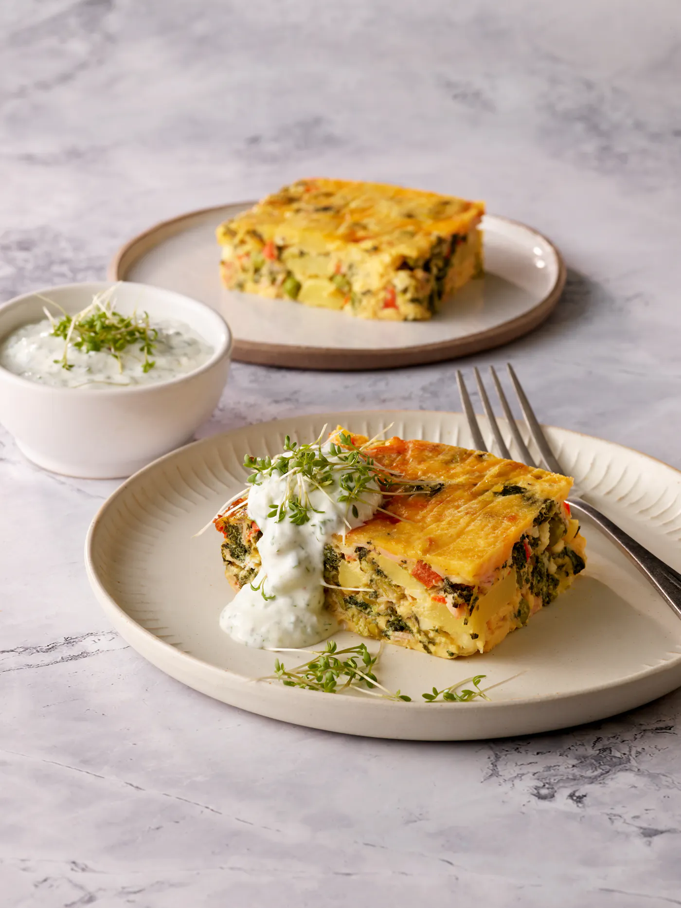 Zwei Teller mit einem herzhaften Breakfast Bake und einem cremigen Skyr-Dip