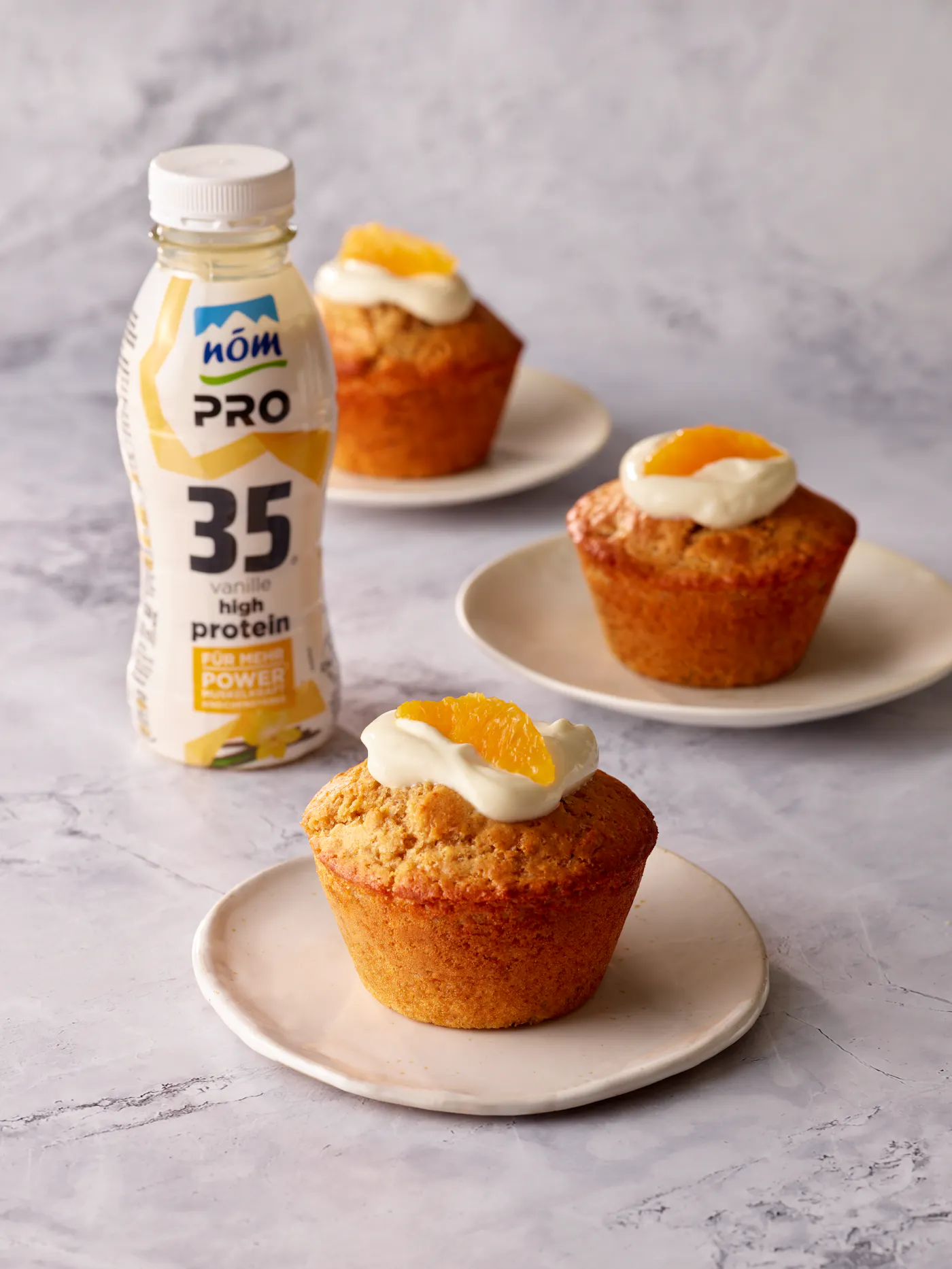 Drei Stück Orangen Muffins mit einem NÖM PRO Proteindrink mit dem Geschmack Vanille