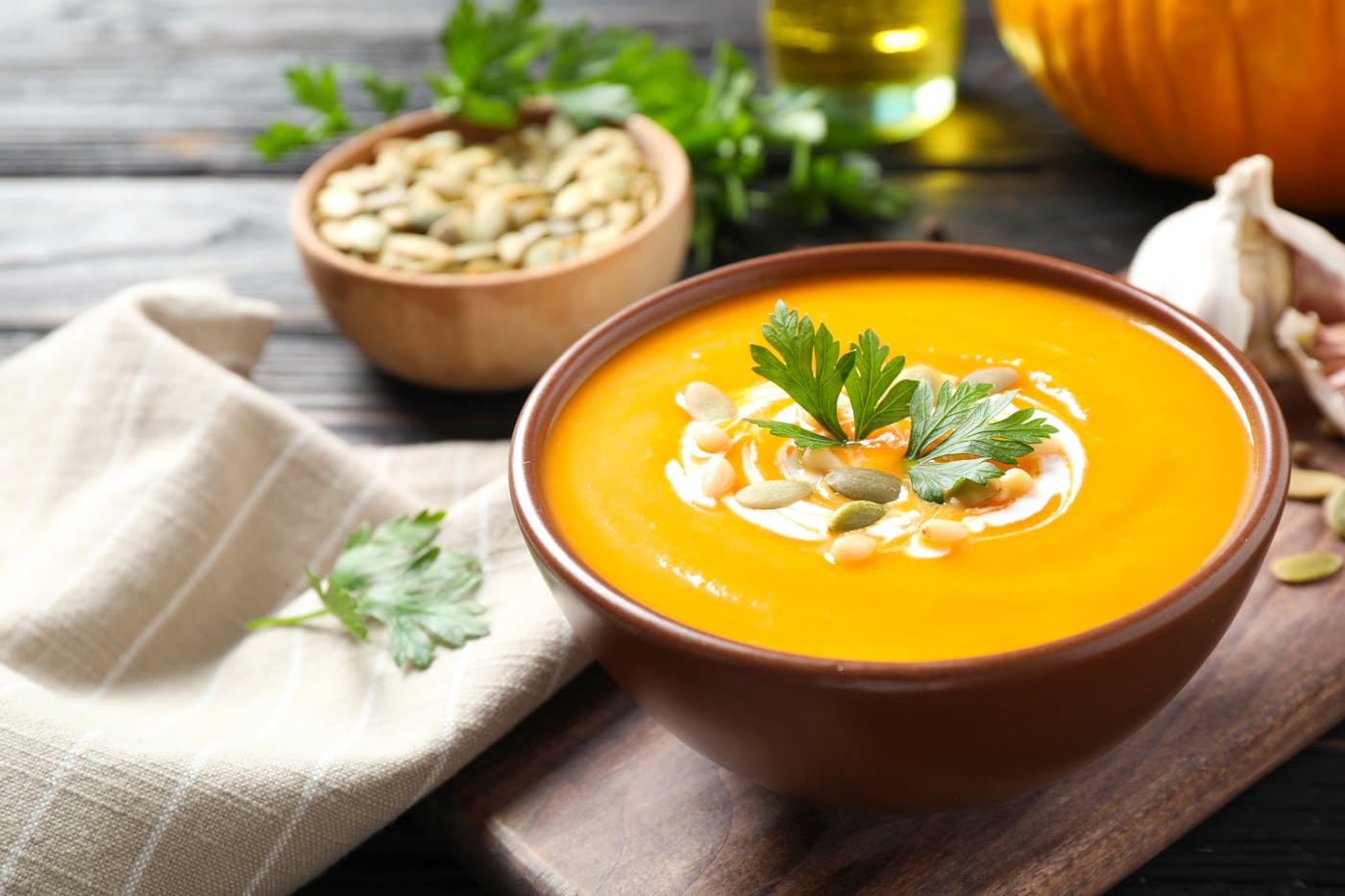 Kuerbiscremesuppe angerichtet mit Schlagobers Kuerbiskernen und Petersilie