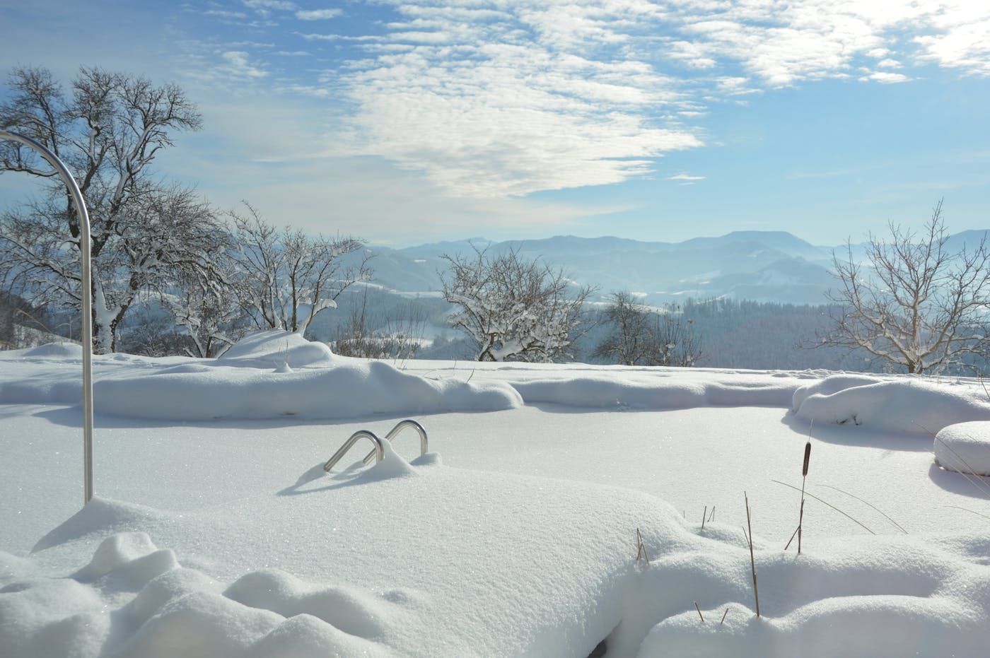 Ein eingeschneiter Pool mit einem traumhaften Ausblick auf eine bergige Landschaft