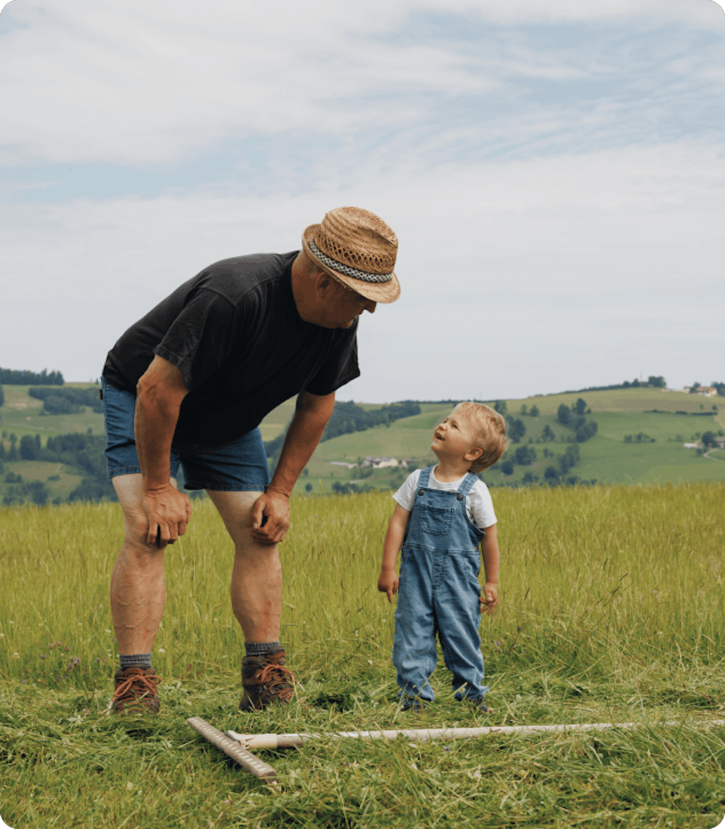 Ein Bauer mit einem Kleinkind steht am Feld