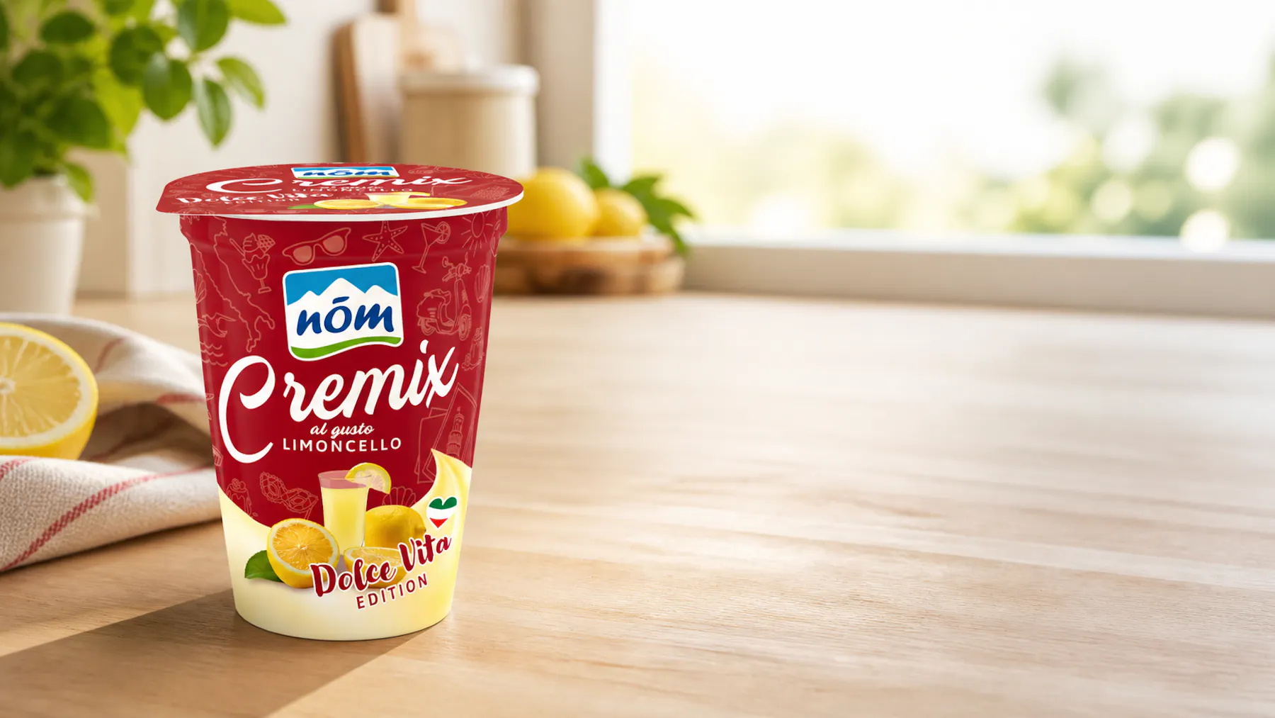 Ein Becher NÖM Cremix steht auf einem hellen Tisch neben einer Zitrone und einem Geschirrtuch Ein Becher NÖM Cremix steht auf einem hellen Tisch neben einer Zitrone und einem Geschirrtuch