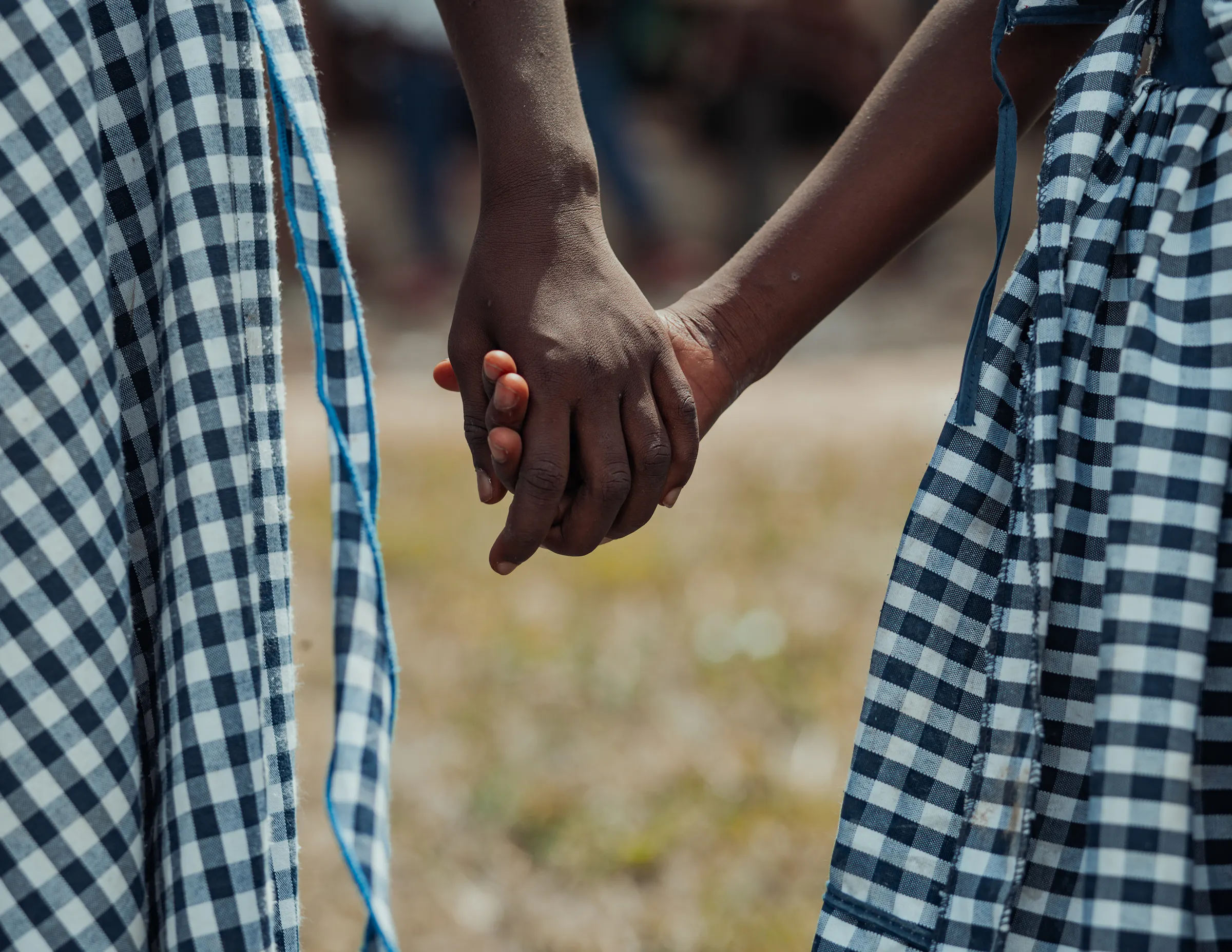 Ein Bild von c Fairtrade Africa, auf dem zwei Frauen im karierten Kleid sich an der Hand halten