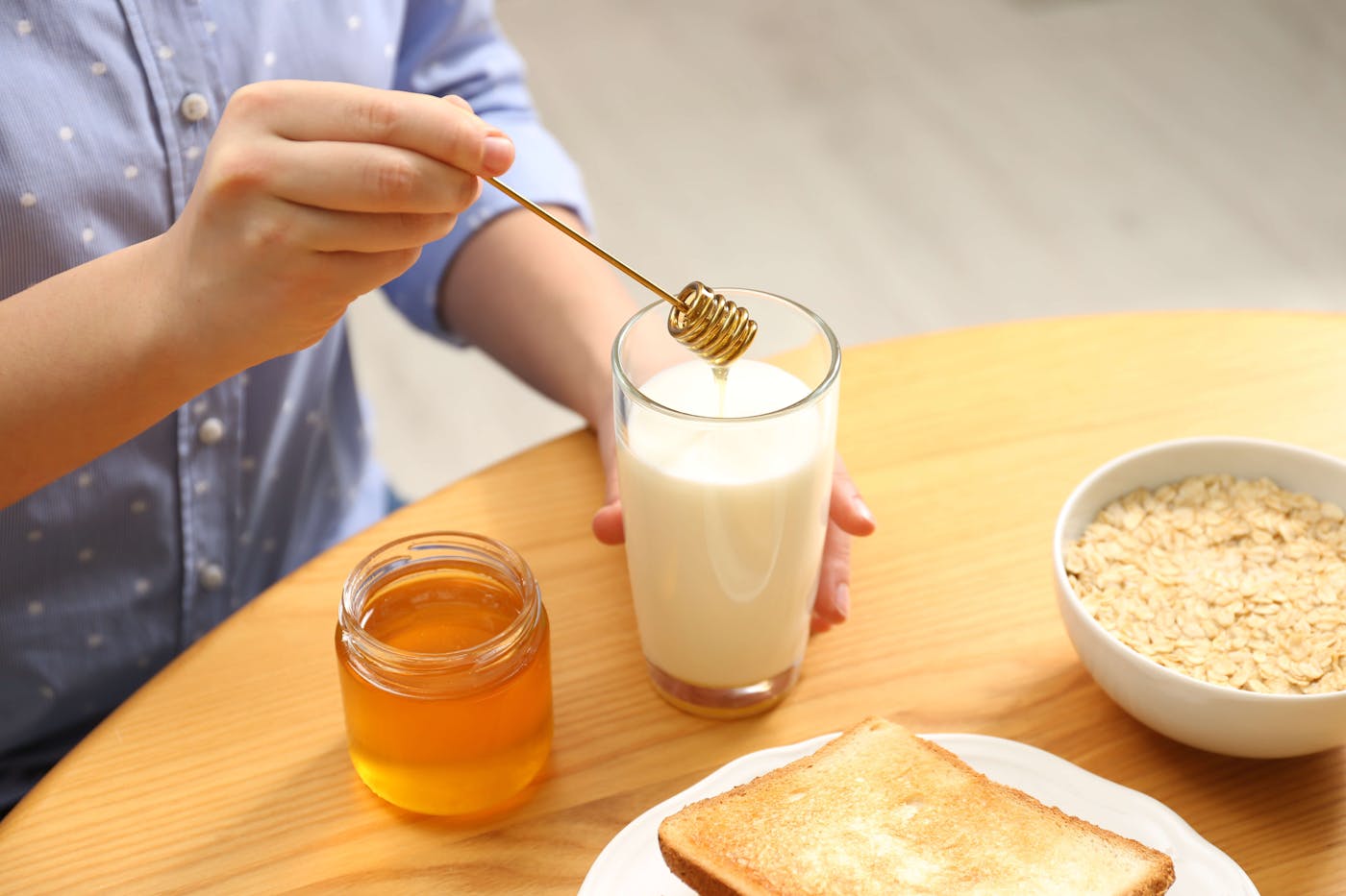 Frau misch Honig in Milch auf Holztisch
