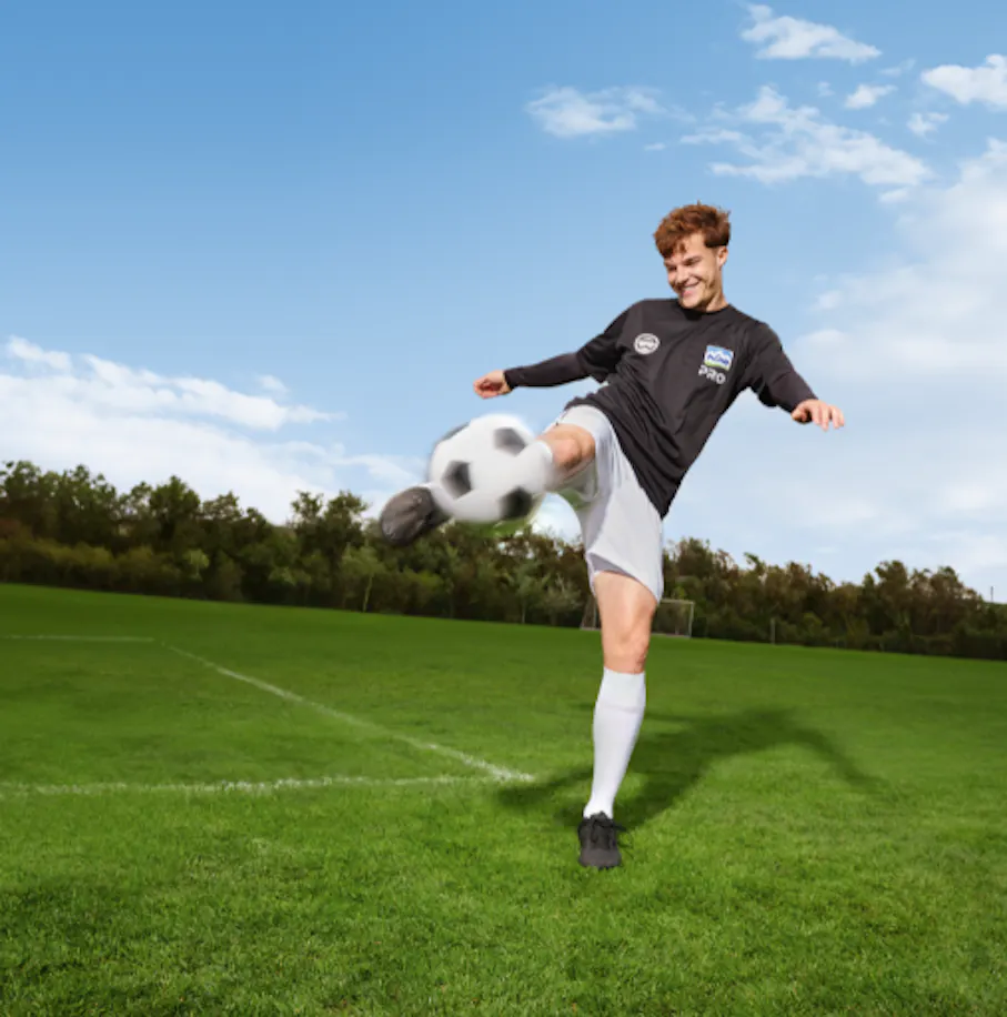 Ein junger Fußballer der Admira trägt ein NÖM PRO Sporttrikot und kickt einen Ball
