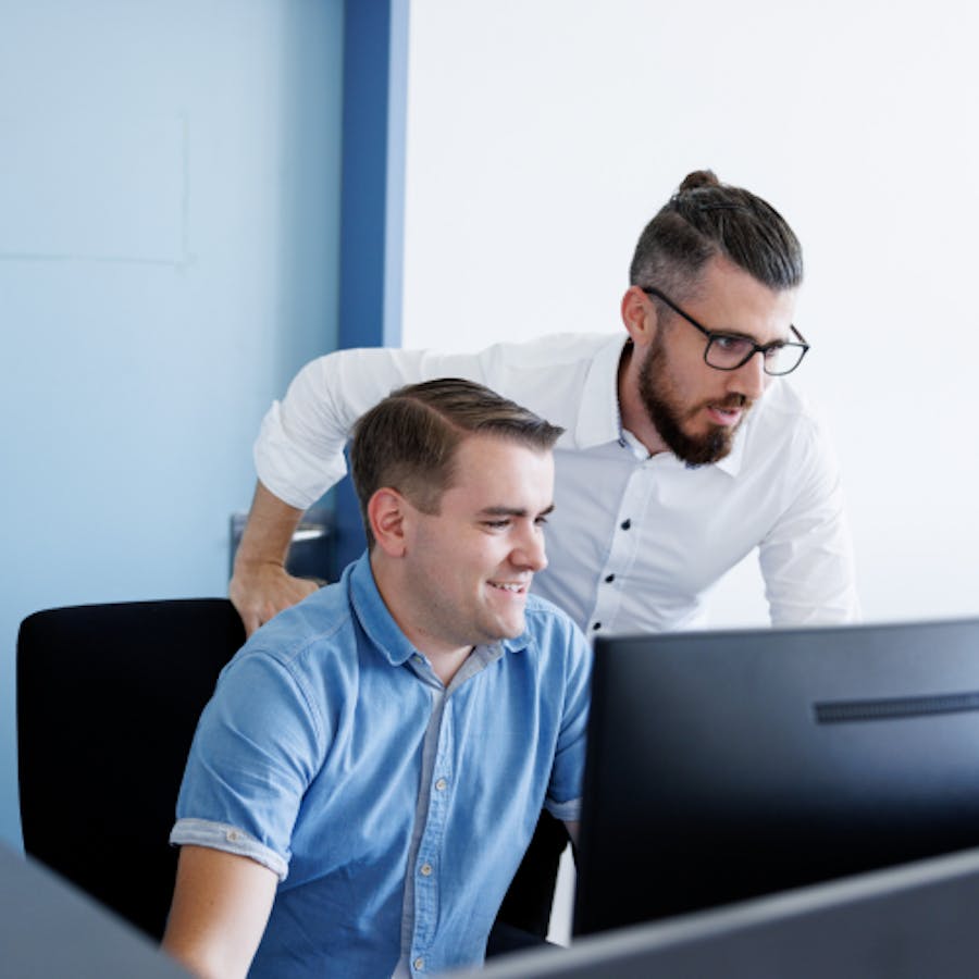 zwei Mitarbeiter der IT-Abteilung sehen zusammen auf einen Bildschirm zwei Mitarbeiter der IT-Abteilung sehen zusammen auf einen Bildschirm