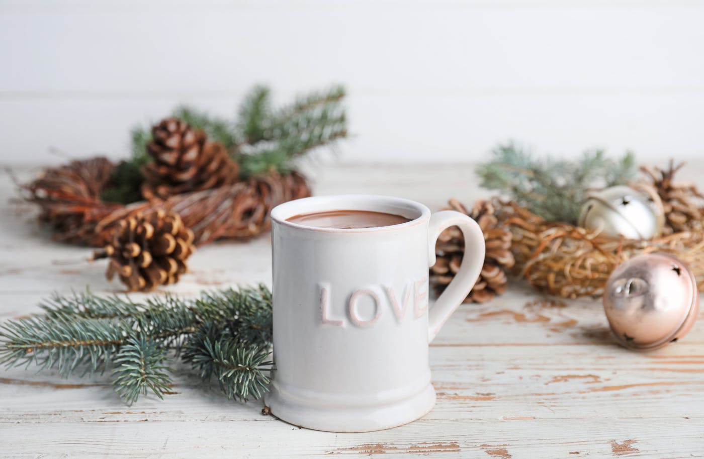 Kakao in weißer Tasse und winterlichen Hintergrund mit Zweigen und Christbaumkugeln Kakao in weißer Tasse und winterlichen Hintergrund mit Zweigen und Christbaumkugeln