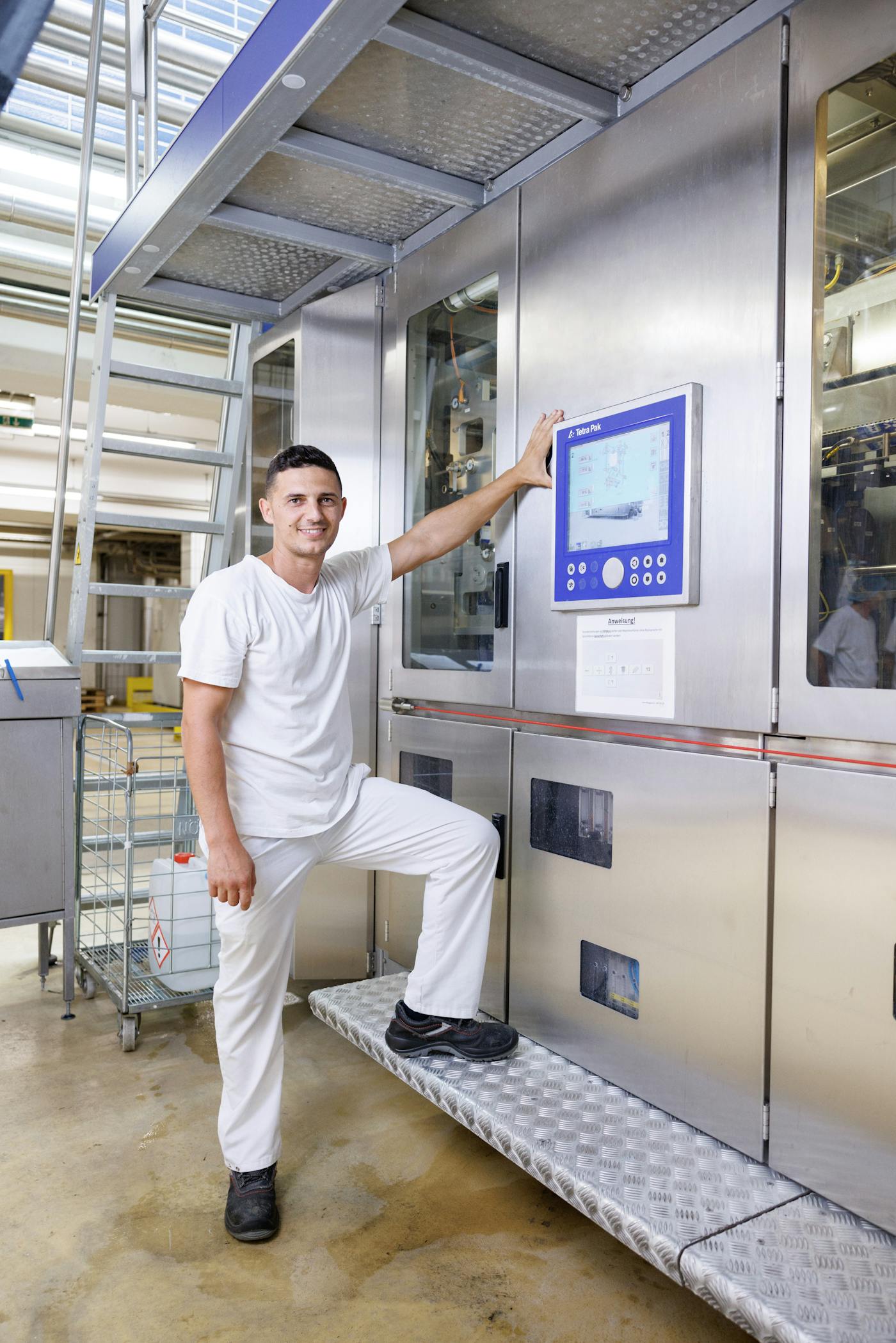 Mitarbeiter der NÖM AG in Hygienekleidung neben einer Maschine Mitarbeiter der NÖM AG in Hygienekleidung neben einer Maschine