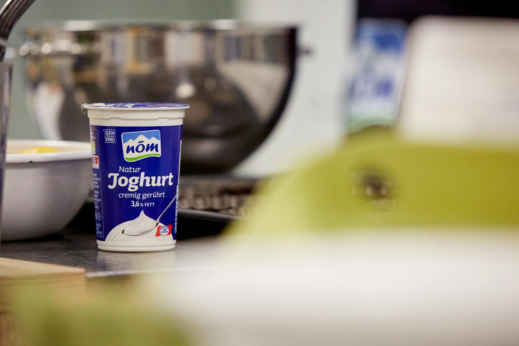 NÖM Natur Joghurt auf Arbeitsplatte mit Küchenutensilien