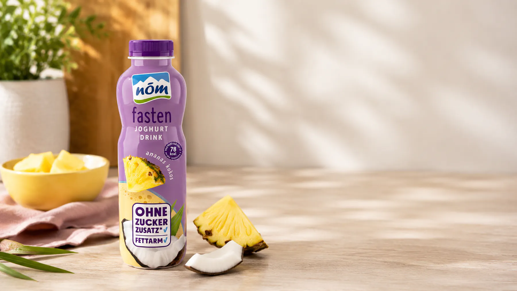 NÖM fasten Joghurtdrink Ananas Kokos mit Ananas und Kokos im Hintergrund