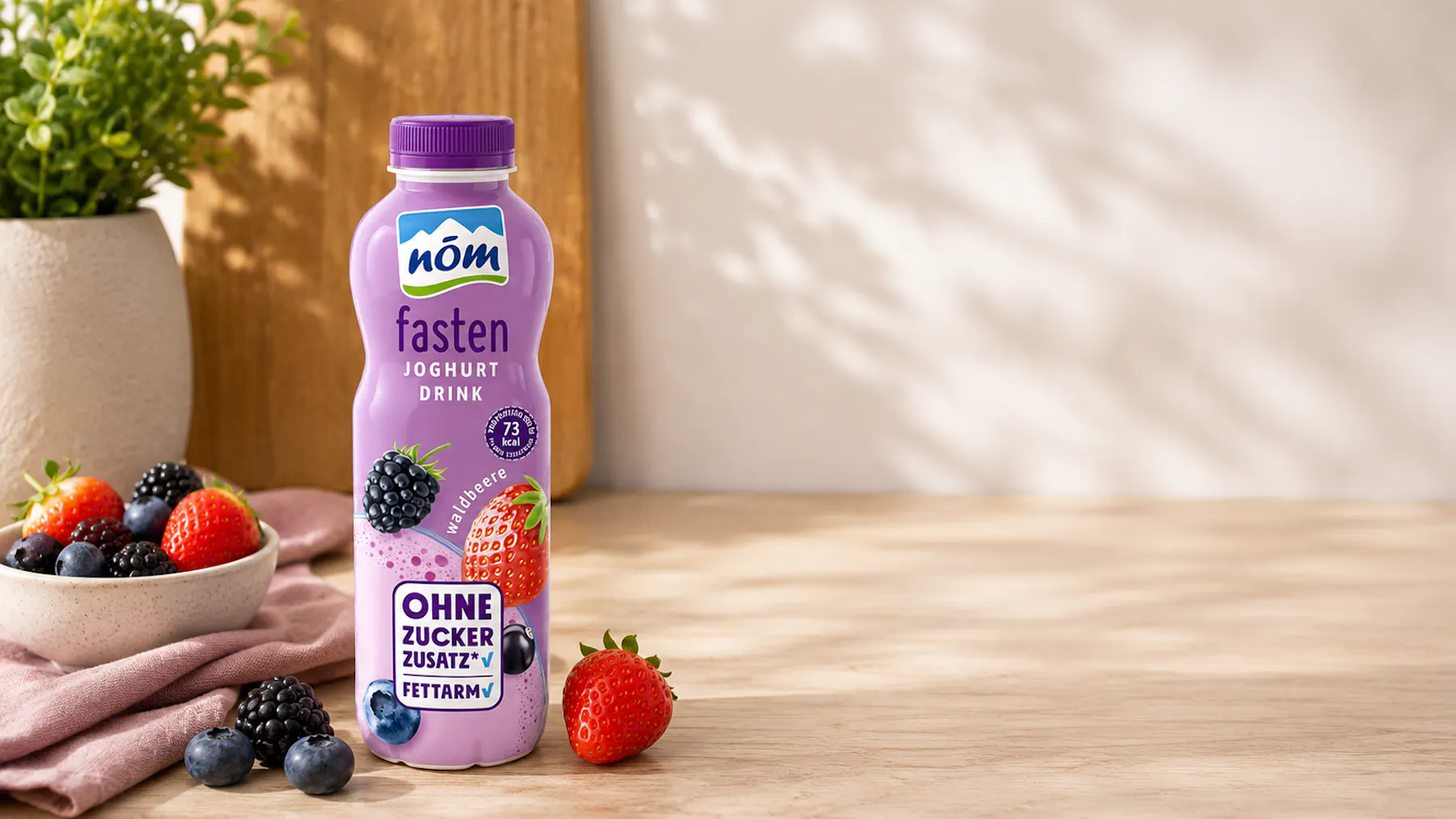 NÖM fasten Joghurtdrink Waldbeere mit frischen Waldbeeren im Hintergrund
