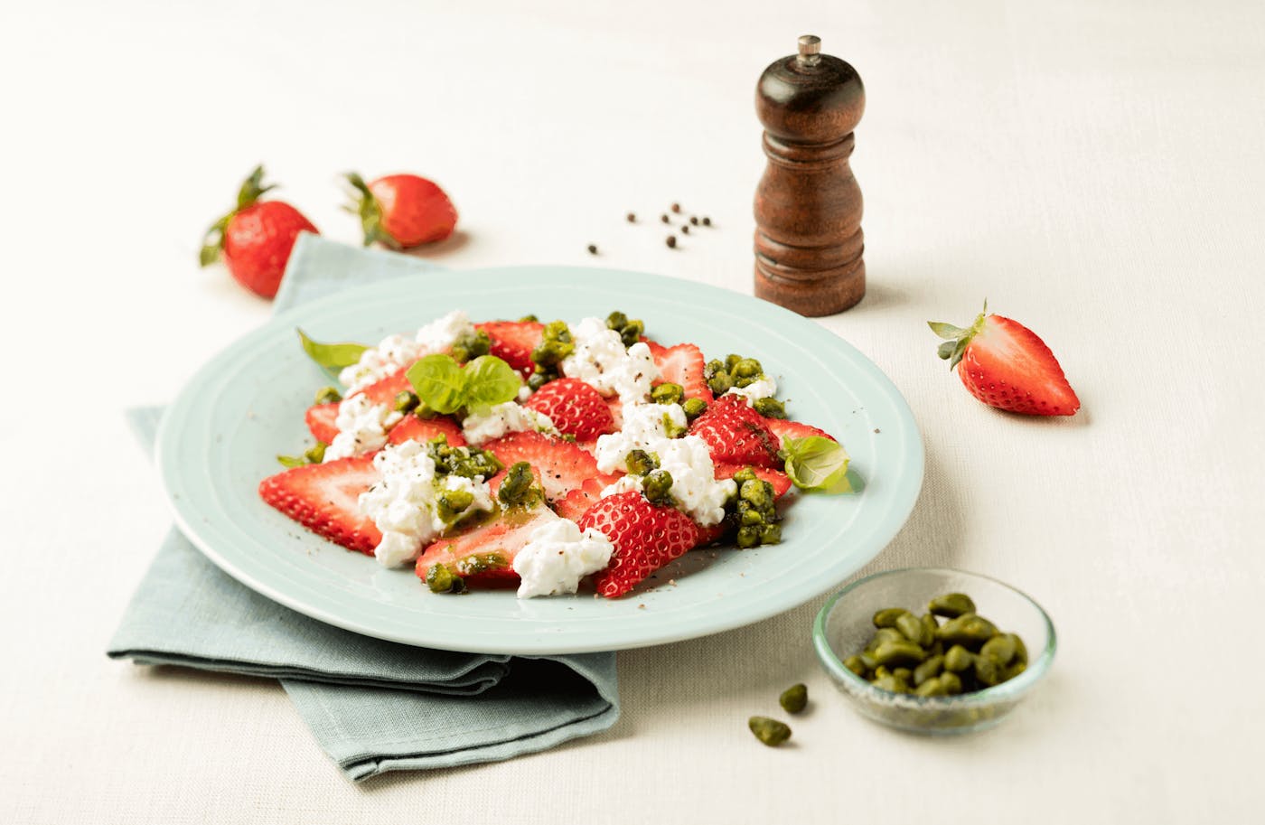 Erdbeer Caprese mit Pistazien und Pfefferstreuer auf dem Tisch Erdbeer Caprese mit Pistazien und Pfefferstreuer auf dem Tisch