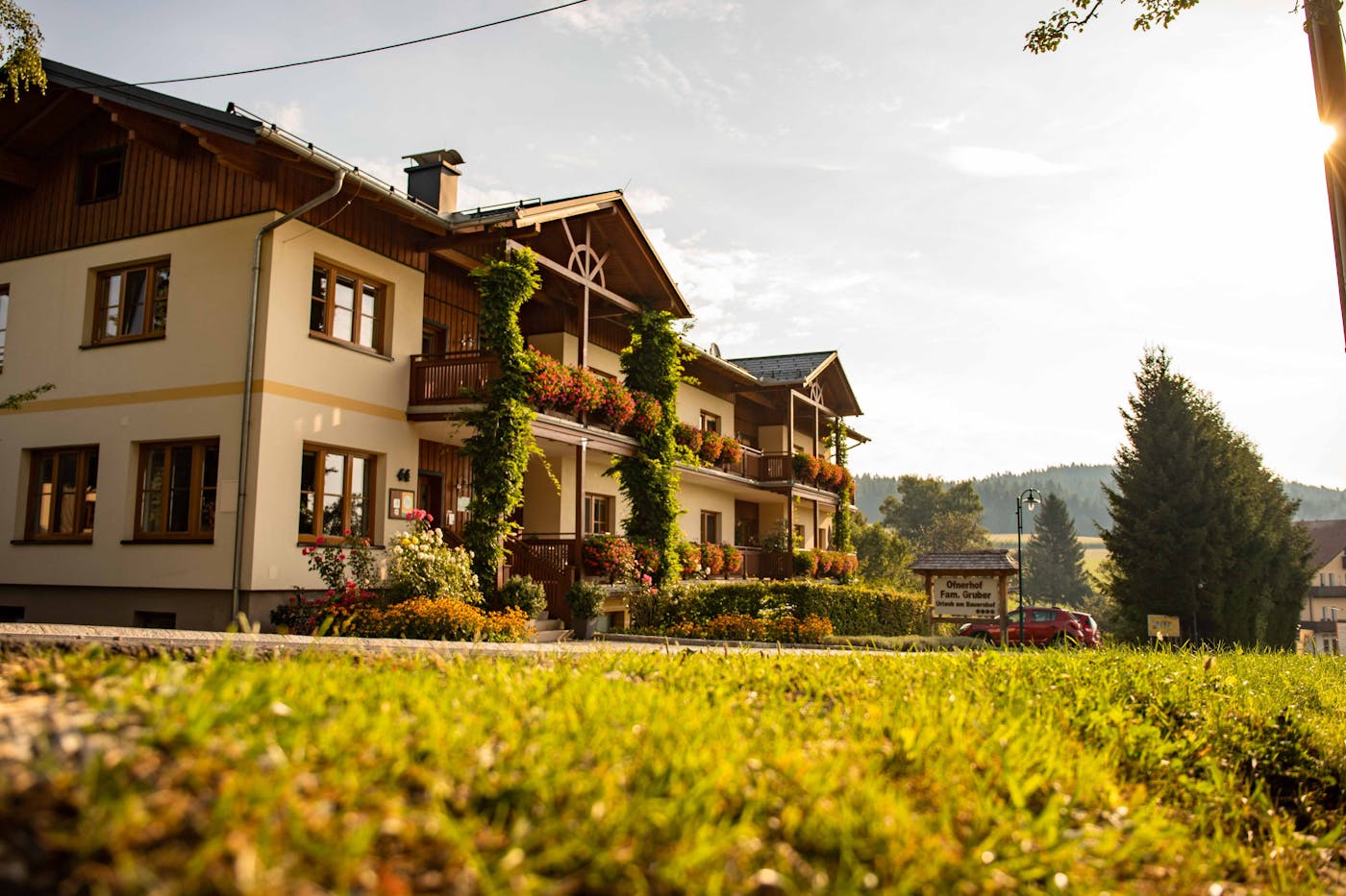 Ofnerhof - Gemütliches Haus im Landhausstil mit Holzbalkonen, reich geschmückt mit bunten Blumen, umgeben von grünem Garten