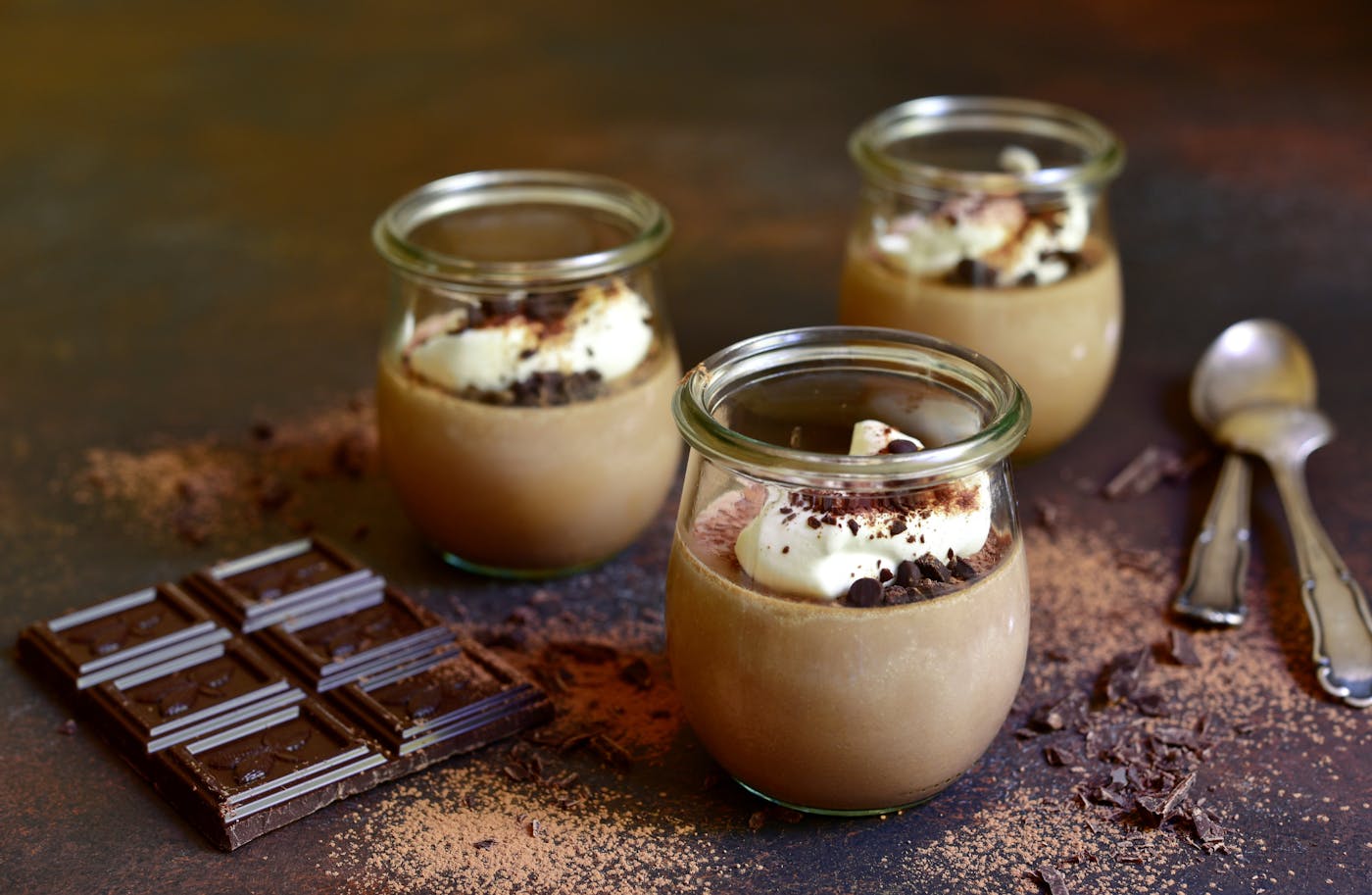 Panna Cotta mit Schlagobers-Topping und Schokodrops im Glas dekoriert mit Schokolade und Schokoraspeln