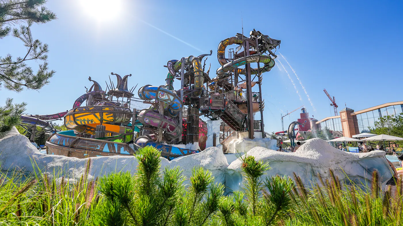 Svalgurok Im Vordergrund ist die Begrünung des Europa-Park Resorts in Rust zu sehen, im Hintergrund ein Fahrgeschäft vor blauem Himmel