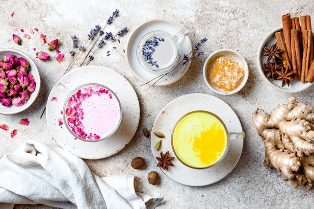 Variationen von Moon Milk in Tassen mit Gewürzen, Blüten und Dekoration