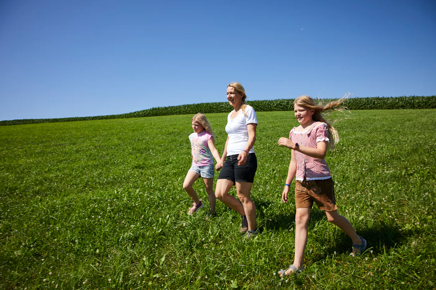 Wiese zwei Mädchen und eine Frau, wie sie über ein Feld spazieren