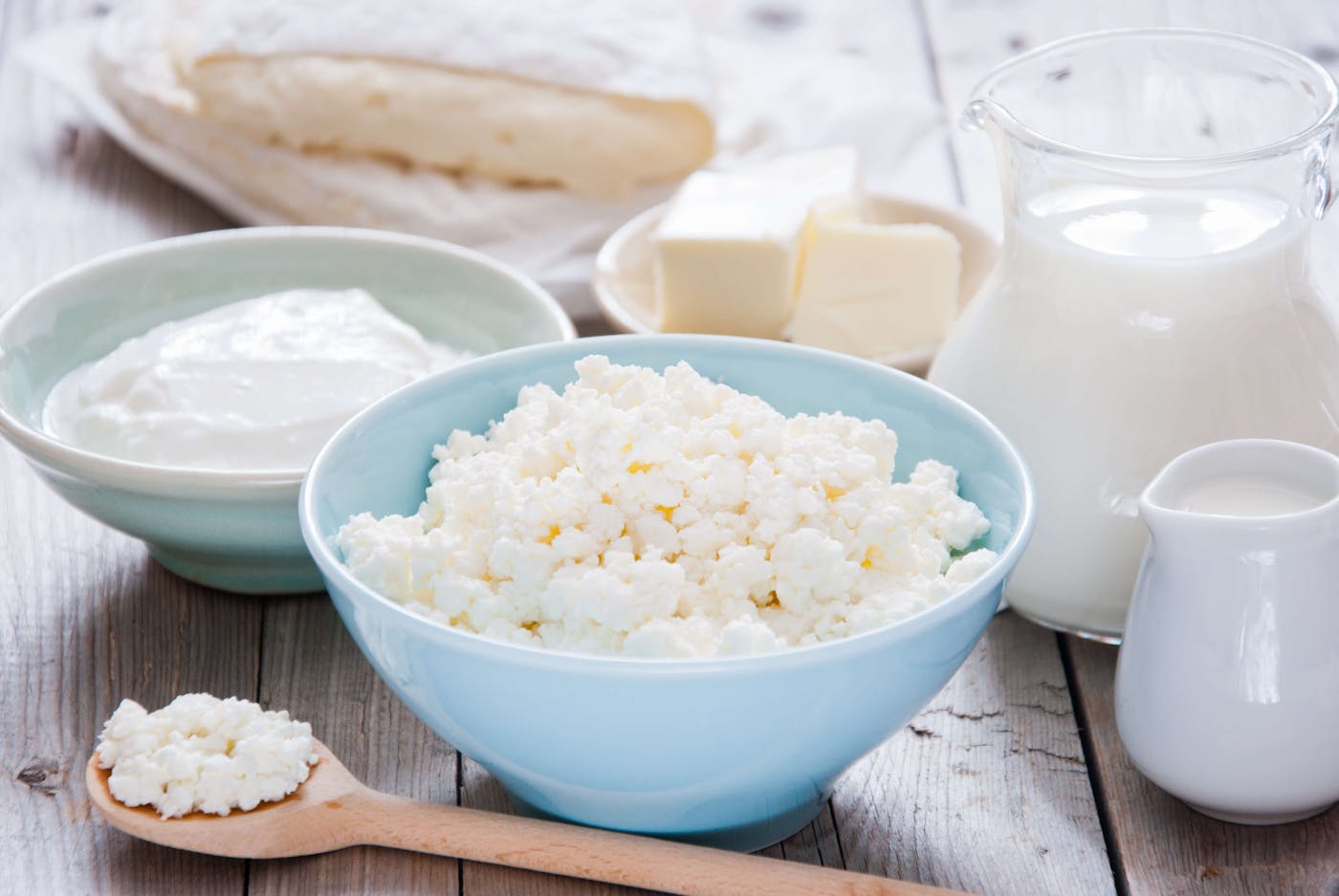 Cottage Cheese, Milch, Käse und andere Milchprodukte stehen in Schüsseln auf einem Holztisch