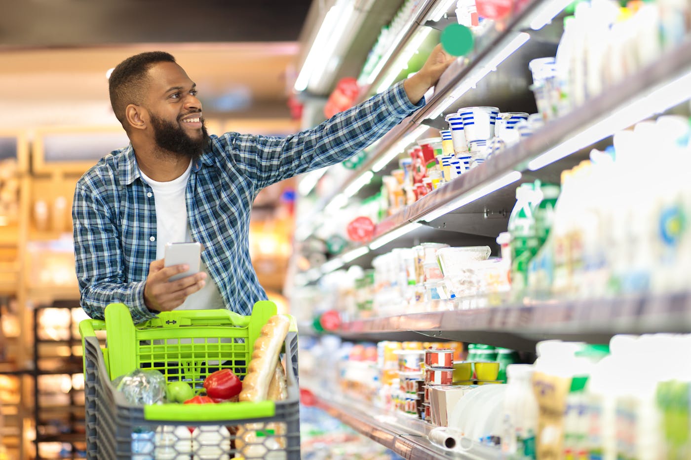 Dunkelhäutiger Mann mit Bart nimmt Supermarktprodukt aus dem Kühlregal