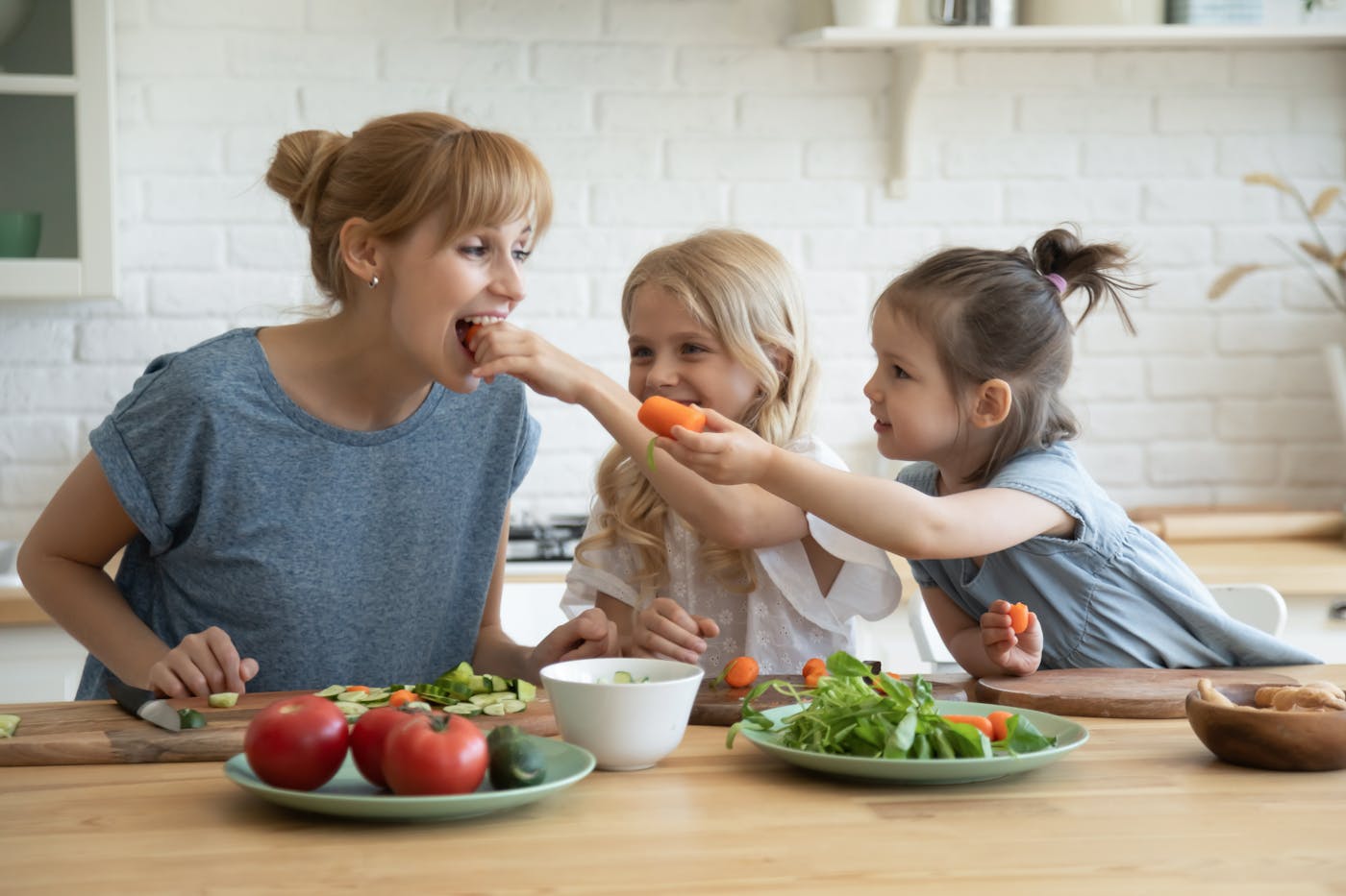 Kinder füttern Mutter mit Gemüsesticks
