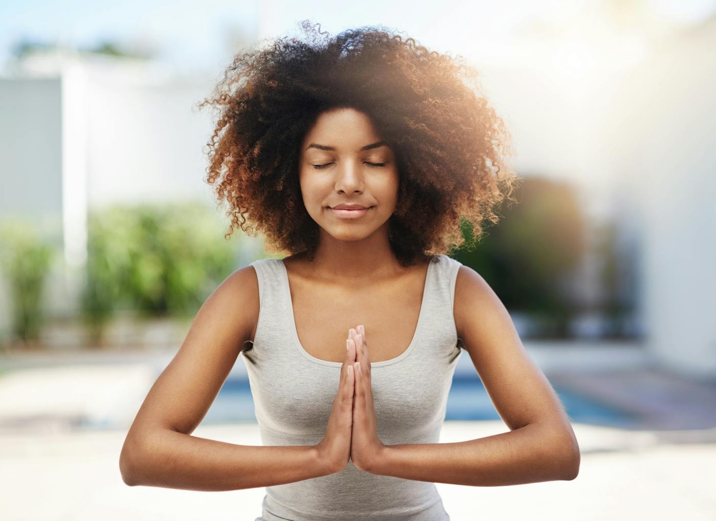 Junge Frau hält Hände in Yoga-Gebetshaltung vor der Brust
