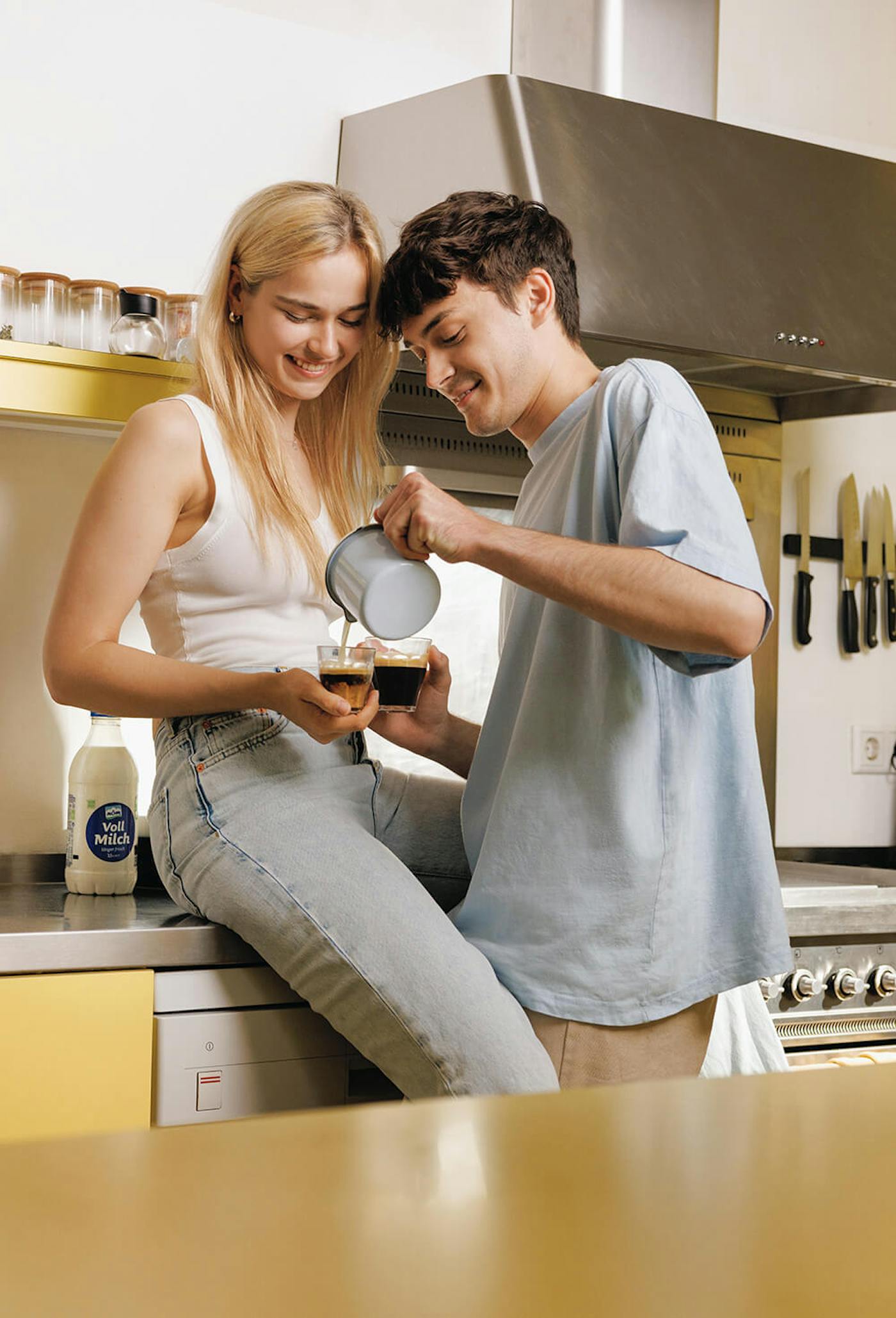 Junges Paar schenkt in Küche Kaffee in Tassen ein Junges Paar schenkt in Küche Kaffee in Tassen ein