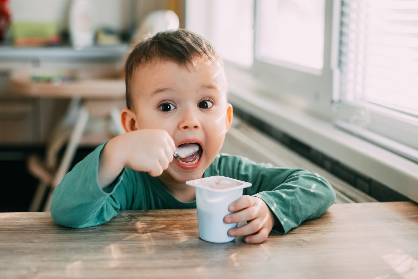 Kleinkind isst Fruchtjoghurt mit Löffel