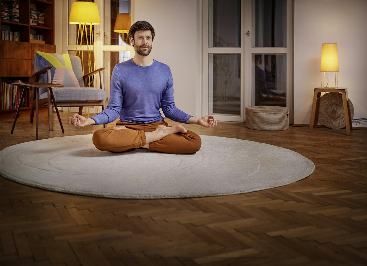 Mann meditiert im Wohnzimmer