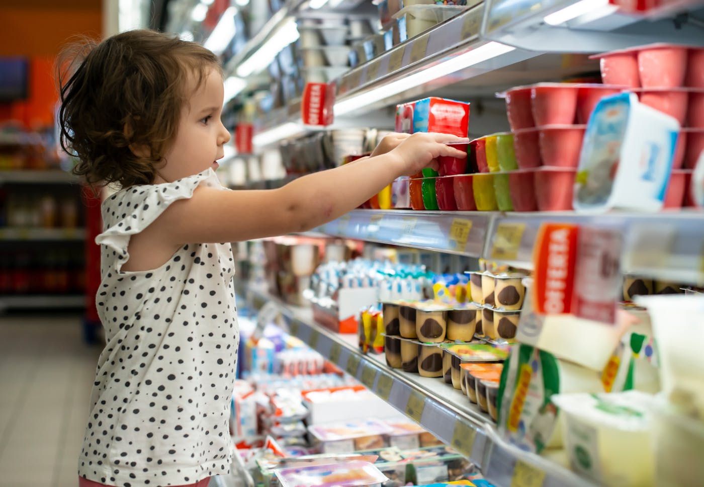 Kleines Mädchen kauft Joghurt im Supermarkt
