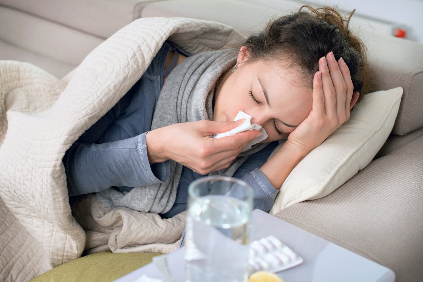 Proteinmangel schwaecht Immunsystem Frau liegt krank auf dem Sofa