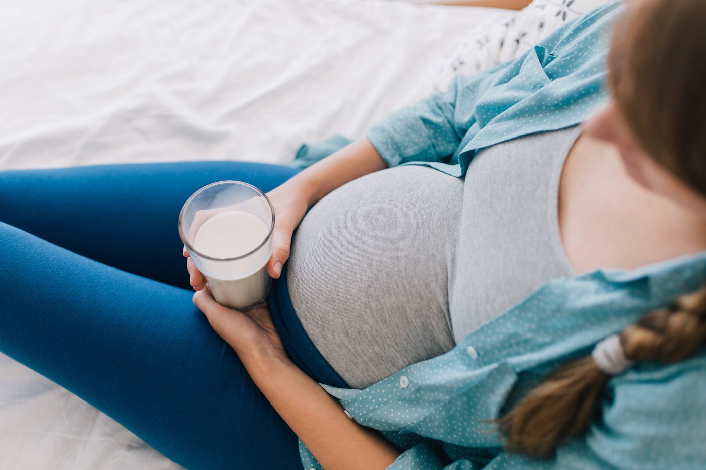 Schwangere rau mit erhöhtem Proteinbedarf hat ein Glas Milch auf ihrem Bauch stehen