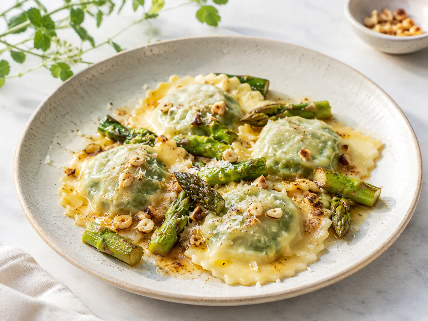 Spinat-Ravioli mit grünem Spargel, brauner Butter und gerösteten Haselnüssen