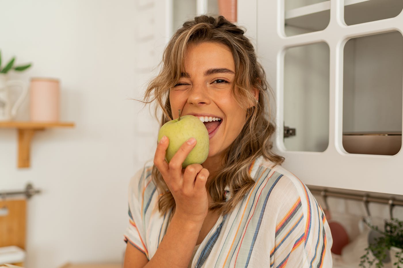 Junge Frau beisst in einen grünen saftigen Apfel