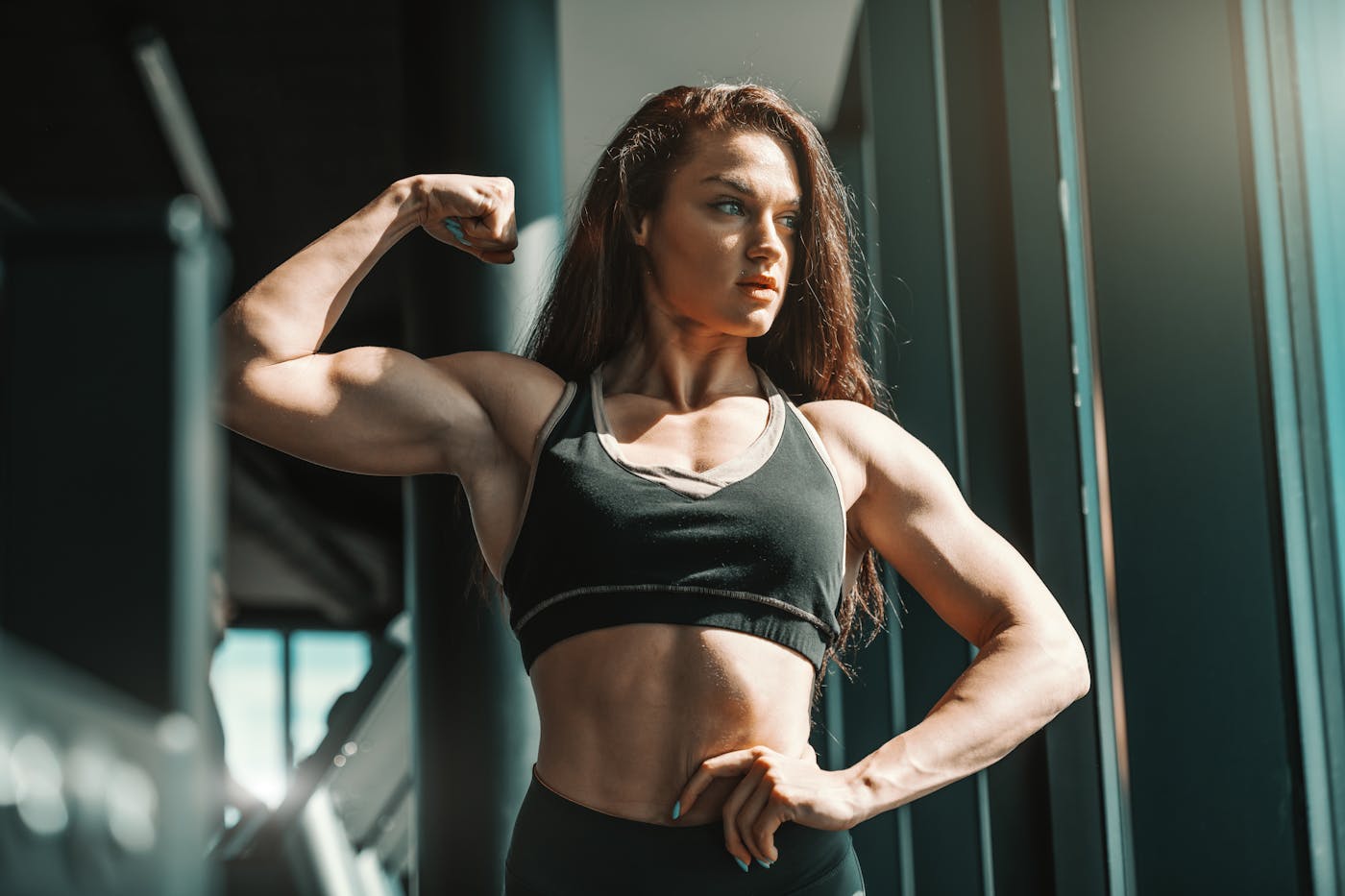 Weibliche Bodybuilderin posiert im Fitnessstudio und zeigt ihre Muskeln
