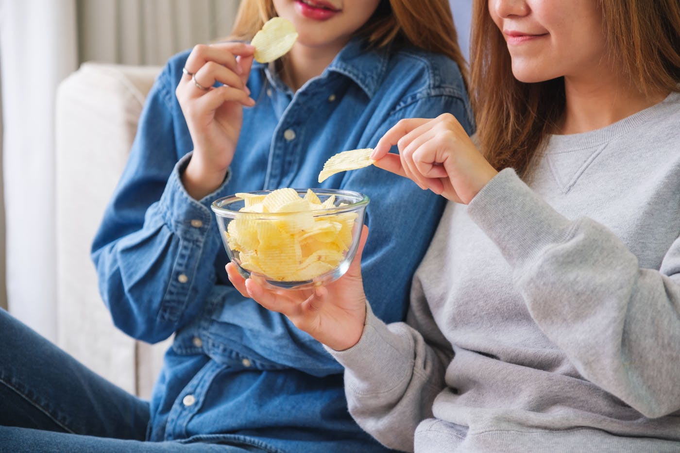Zwei Frauen essen Chips aus einer Glasschüssel